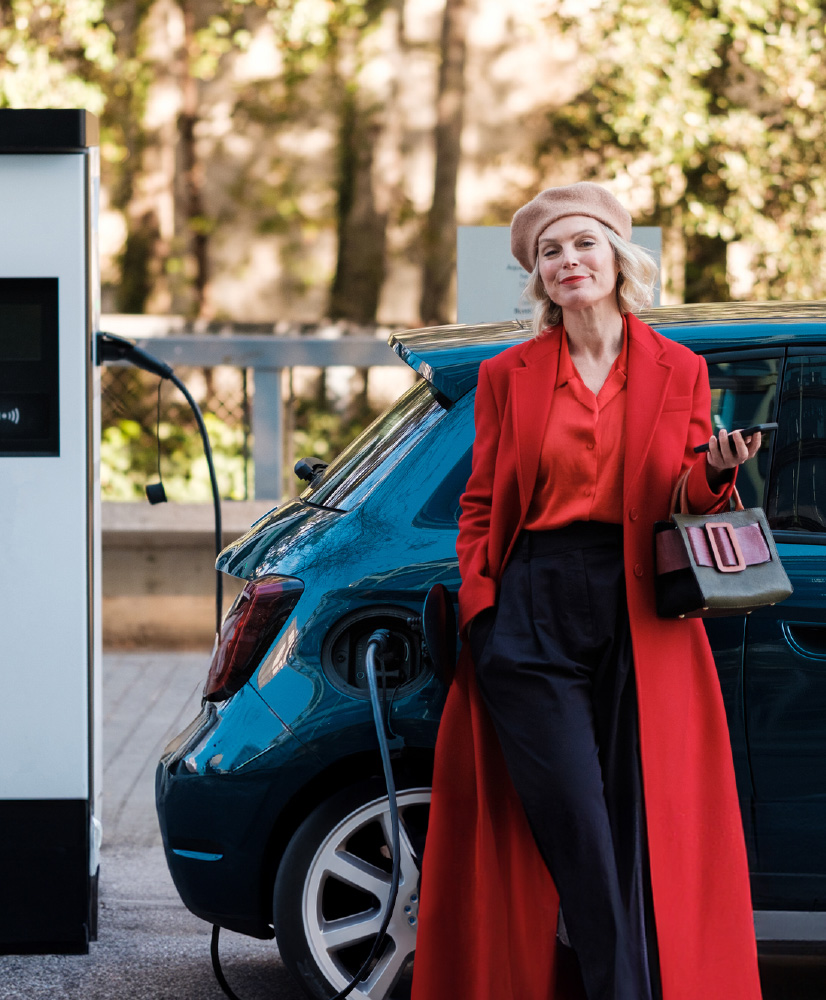 A businesswoman next to a new electric car financed with car leasing business or operational leasing.