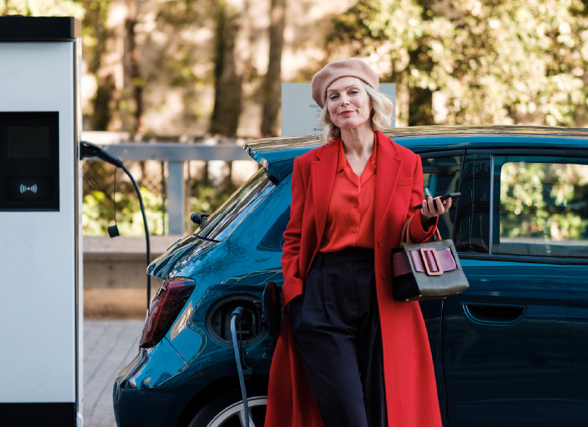 A businesswoman next to a new electric car financed with car leasing business or operational leasing.